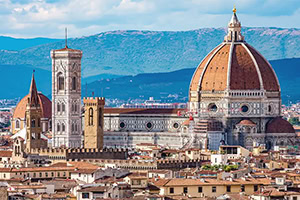 Vista panorâmica de Florença com a Catedral de Santa Maria del Fiore e a sua grande cúpula em primeiro plano, com montanhas ao fundo